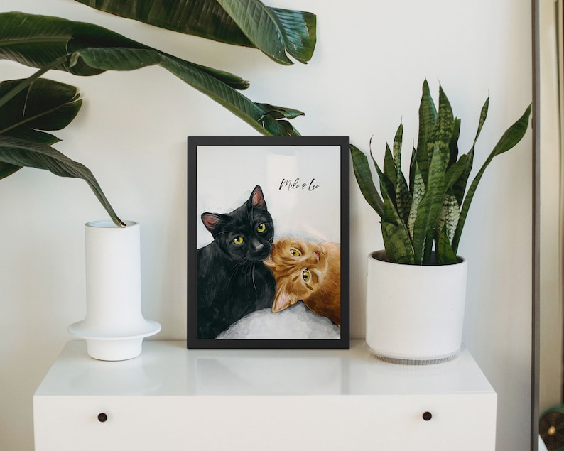K&ouml;nnte beinhalten: Gerahmtes Bild von zwei Katzen, eine schwarze und eine orange, mit dem Text "Milo & Leo" dar&uuml;ber.