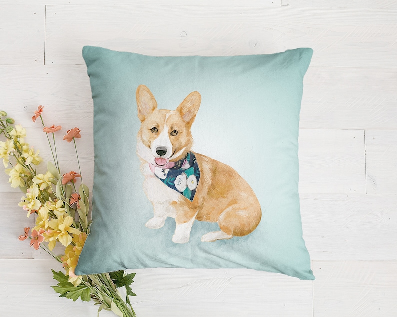 May include: A light blue throw pillow with a watercolor illustration of a corgi wearing a floral bandana. The corgi is looking to the right and has a pink tongue sticking out.