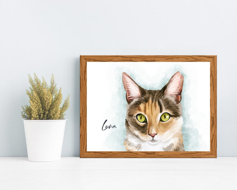 K&ouml;nnte beinhalten: Ein gerahmtes Aquarellbild einer Katze namens Luna. Die Katze hat gr&uuml;ne Augen, braunes und orangefarbenes Fell und einen wei&szlig;en Fleck auf der Brust. Der Hintergrund ist ein hellblauer Aquarell-Wasch.