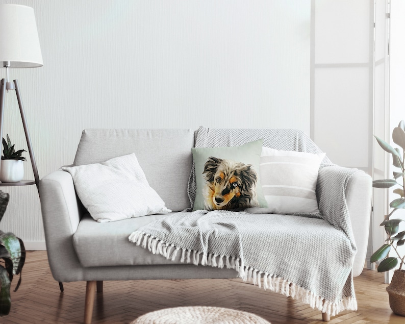 May include: A gray couch with a throw blanket and a pillow featuring a watercolor painting of a dog's face.