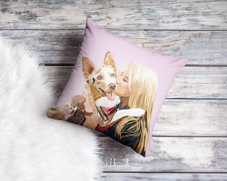 May include: A pink throw pillow with a watercolor illustration of a woman kissing a dog. The dog is brown and white with blue eyes. The woman has long blonde hair.