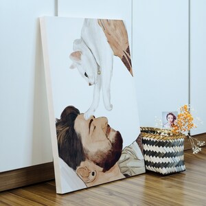 K&ouml;nnte beinhalten: Ein Aquarellbild einer Person mit einer wei&szlig;en Katze auf der Brust. Die Katze schaut auf die Person, die die Katze anschaut. Das Bild ist auf Leinwand gemalt und gerahmt.