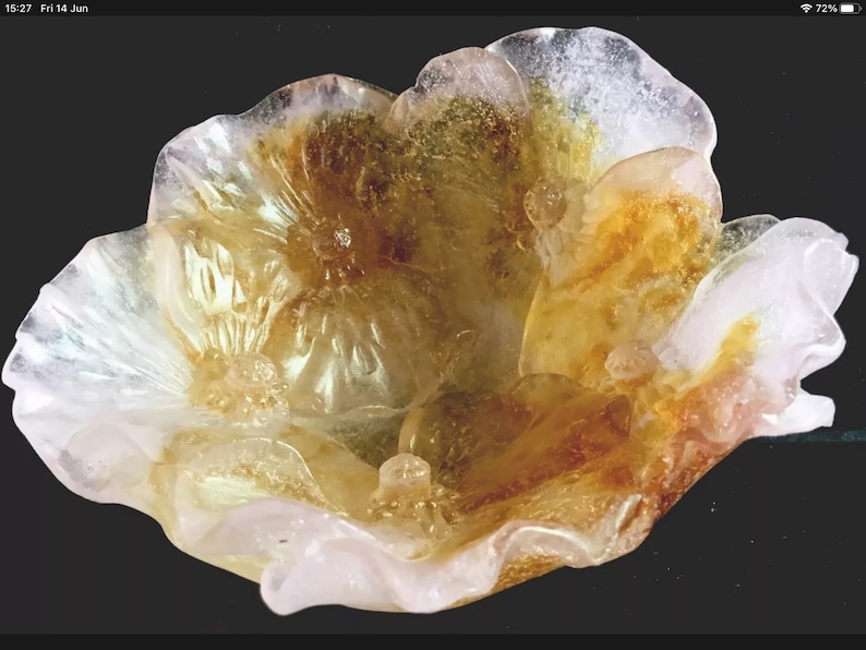 May include: A delicate, translucent flower-shaped bowl made of glass. The bowl has a white and yellow color scheme with a subtle pink hue. The glass is textured and has a slightly iridescent quality.