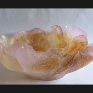 May include: A pink and orange glass bowl shaped like a flower with a textured surface.