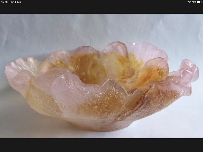 May include: A pink and orange glass bowl shaped like a flower with a textured surface.
