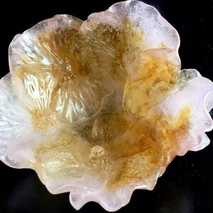 May include: A delicate, translucent flower-shaped bowl made of glass. The bowl has a pink and yellow color scheme with intricate details.
