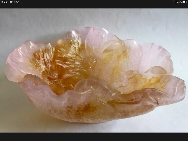 May include: A pink and amber glass bowl shaped like a flower. The bowl has a textured surface and a delicate, feminine design.