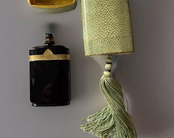 May include: A vintage perfume bottle with a black glass body and gold accents, in a green leather case with a tassel.