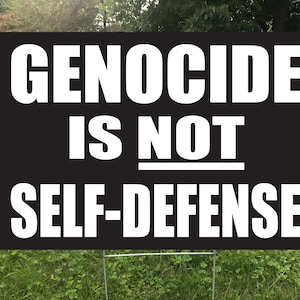 May include: Black and white sign with the text "GENOCIDE IS NOT SELF-DEFENSE" in bold white letters.