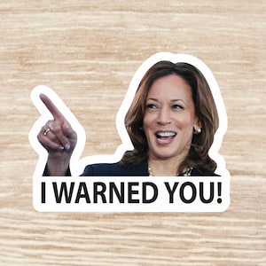May include: A white sticker with a woman pointing with her right index finger. The woman has long dark brown hair and is wearing a dark blue blazer. The text on the sticker reads "I WARNED YOU!"