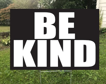 May include: Black and white yard sign with the text "BE KIND" in large, bold, white letters.