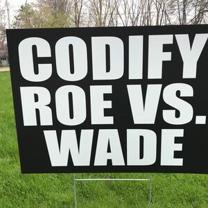 May include: Black and white yard sign with the text "CODIFY ROE VS. WADE" in bold white letters.