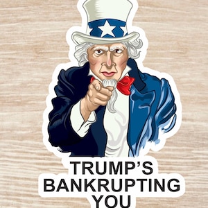 May include: A sticker featuring a cartoon Uncle Sam pointing at the viewer with a stern expression. The sticker has the text "TRUMP'S BANKRUPTING YOU" in black letters on a white background.
