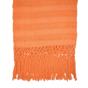 Może przedstawiać: Jasny pomarańczowy, tkany szal z frędzlami. Szal jest wykonany z miękkiej, lekkiej tkaniny i ma delikatny, skomplikowany wzór.