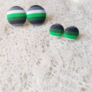 May include: A set of four fabric button earrings. The larger earrings are green, white, and gray striped. The smaller earrings are green, black, and white striped.