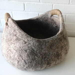 Felted wool storage basket in grey with two wrapped handles; cozy cat bed with a sleeping cat inside.