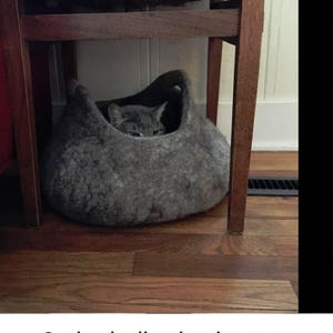 Felted wool storage basket in grey with two wrapped handles; cozy cat bed with a sleeping cat inside.