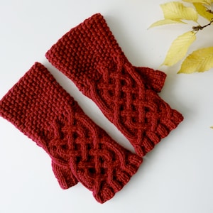 May include: A pair of red knitted fingerless gloves with a cable knit pattern.