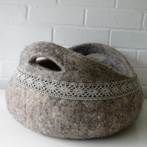 Felted storage basket with linen lace trim and handles; neutral brown felt, ideal as magazine bin or cat bed.