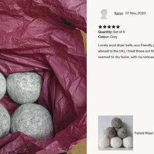 Felted wool dryer balls stacked in white and gray against a white brick wall; natural, allergy-free, eco-friendly fabric softener.