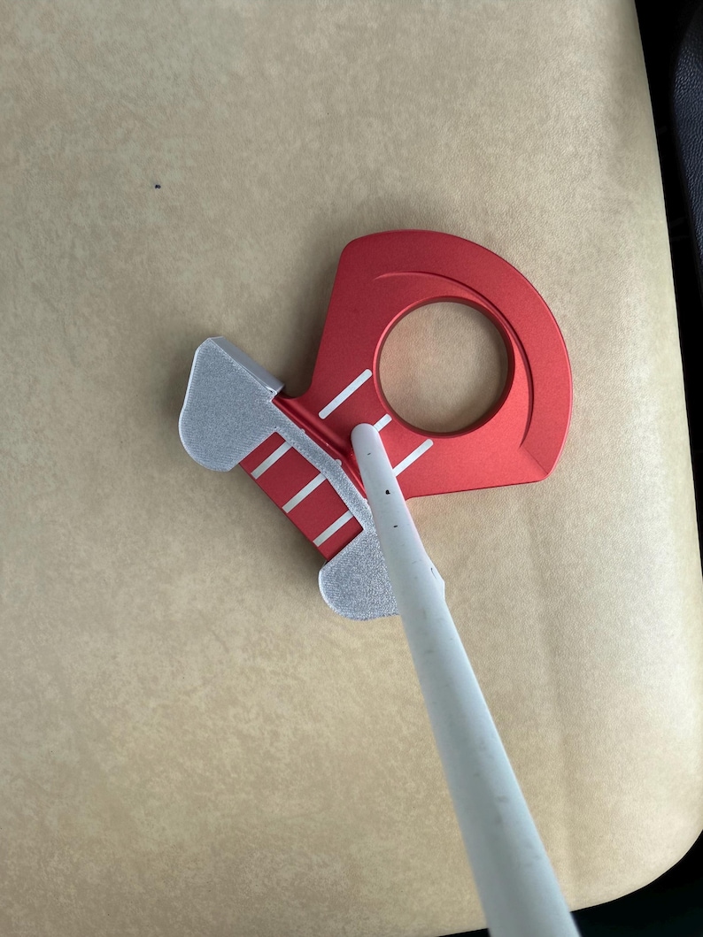 May include: Red and silver metal tool with a circular opening and a pointed white object. The tool has a red body with white stripes and a silver section. The white object is long and cylindrical.