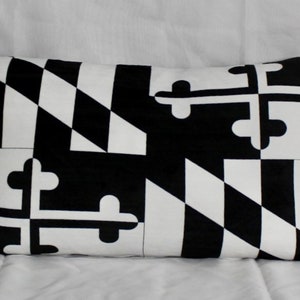May include: Black and white throw pillow with a geometric pattern resembling the Maryland state flag.
