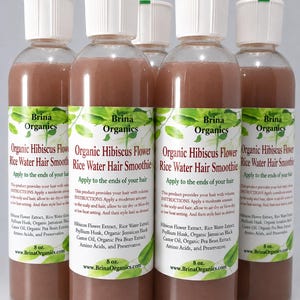 Könnte beinhalten: Fünf durchsichtige Kunststoffflaschen gefüllt mit einer bräunlichen Flüssigkeit, jeweils mit weißem Verschluss. Die Etiketten tragen die Aufschrift Brina Organics Organic Hibiscus Flower Rice Water Hair Smoothie, Inhaltsstoffe und Anweisungen, 227 Gramm.