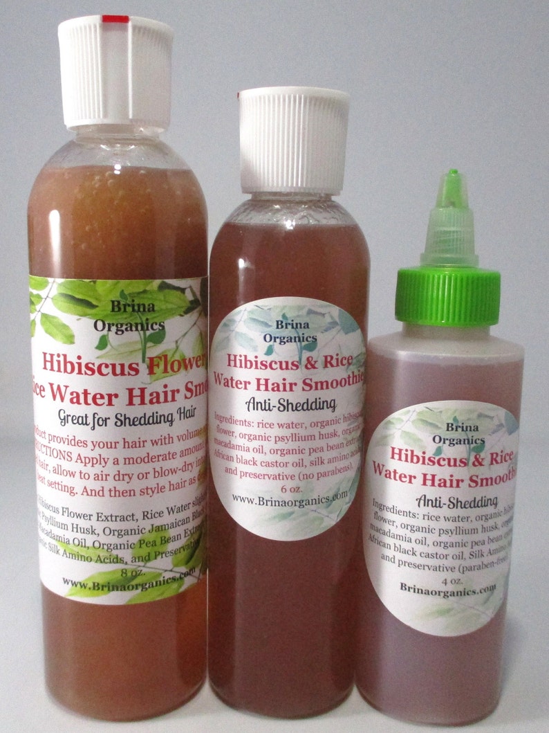 May include: Three clear plastic bottles of Brina Organics Hibiscus & Rice Water Hair Smoothie. The bottles are labeled with ingredients and instructions, featuring sizes of 8 oz., 6 oz., and 4 oz. The liquid inside is a translucent reddish-brown color.