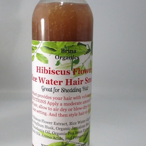 May include: A clear plastic bottle filled with a brownish liquid, topped with a white cap. The label reads Brina Organics Hibiscus Flower Rice Water Hair Smoothie, Great for Shedding Hair, and lists ingredients including 8 oz. net weight.