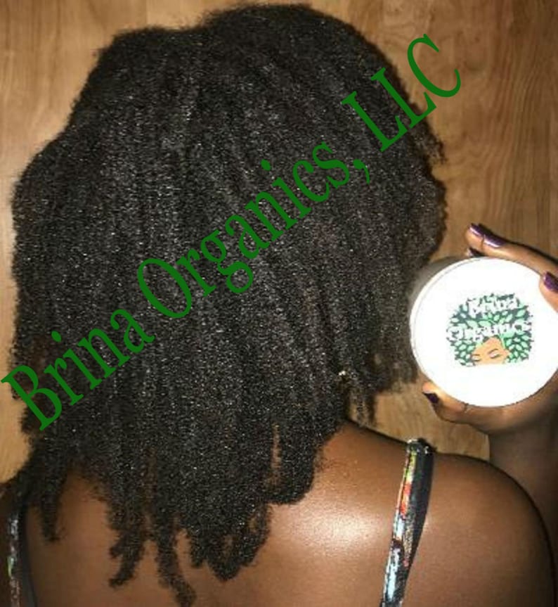 May include: A round white container with a label featuring a green graphic of a person with curly hair and the text Brina Organics. The container is held near dark, textured, curly hair that falls to the shoulders, with the text Brina Organics, LLC.