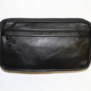 Puede incluir: Una riñonera de cuero negro con un bolsillo con cremallera y un cierre de hebilla.