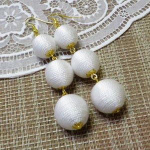 Op de afbeelding: Witte zijden kwast oorbellen met gouden accenten. De oorbellen zijn gemaakt van meerdere lagen zijden ballen.