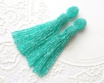 May include: A pair of turquoise beaded tassel earrings. The tassels are made of small, iridescent beads and are approximately 7.5 cm long.