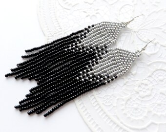 May include: Long black and silver beaded earrings with a fringe design. The earrings are approximately 3 inches long.