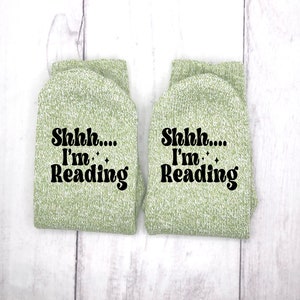 May include: A pair of green socks with the text "Shhh... I'm Reading" in black.