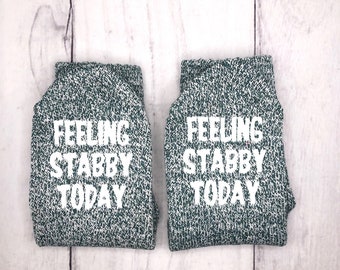 May include: A pair of green socks with white text that reads "Feeling Stabby Today".