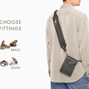 May include: A black leather crossbody phone pouch with a wide shoulder strap featuring a vertical zippered pocket. The text CHOOSE FITTINGS appears next to two metal button options: brass and silver, shown as two-piece sets for attachment.
