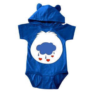 May include: A blue hooded baby onesie with a white bear face and a blue cloud with red hearts. The bear face has a blue cloud with raindrops and red hearts.