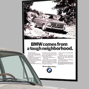 Peut inclure: Publicité vintage en noir et blanc pour BMW. L'annonce présente une voiture BMW classique sur une route de terre, avec le texte "BMW vient d'un quartier difficile". Le logo Bavarian Motor Works est également visible.