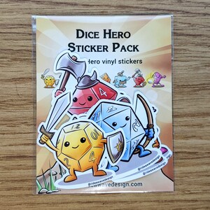 May include: A clear plastic package containing a sticker pack. The stickers feature cartoon dice characters with weapons and shields. Text on the package reads "Dice Hero Sticker Pack". The stickers are on a gradient background.