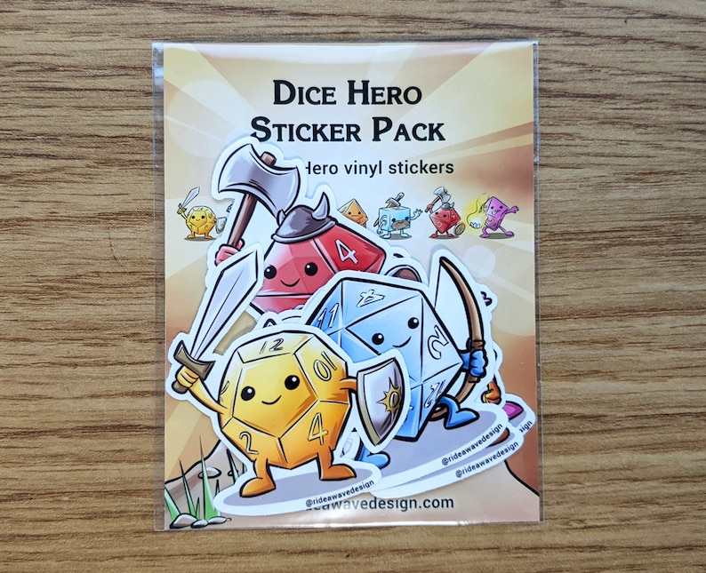 May include: A clear plastic package containing a sticker pack. The stickers feature cartoon dice characters with weapons and shields. Text on the package reads "Dice Hero Sticker Pack". The stickers are on a gradient background.