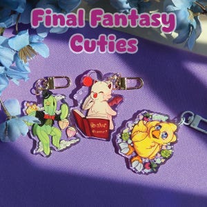 May include: Three acrylic keychains featuring Final Fantasy characters. The keychains include a green cactus, a white cat-like creature with red accents, and a yellow chick. The text "Final Fantasy Cuties" is at the top.