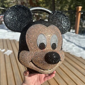 May include: A black and gold rhinestone-covered Mickey Mouse head handbag with a black handle.