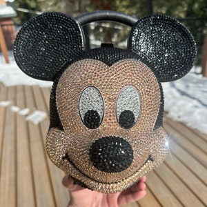 May include: A black and gold rhinestone-covered Mickey Mouse purse with a black handle.