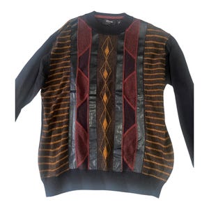 May include: A black sweater with long sleeves and a patterned front. The front features vertical panels of burgundy, brown, and black leather-like material, with diamond and striped designs. The sleeves are solid black.