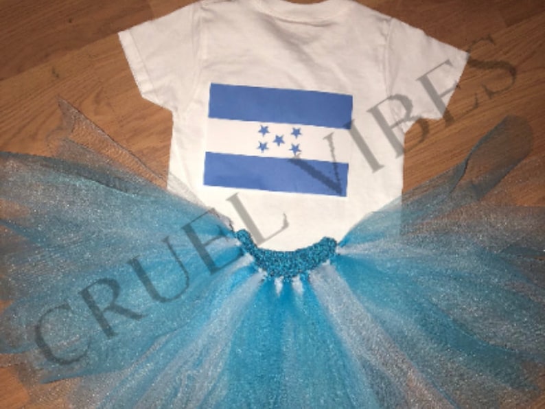 May include: A white t-shirt with a blue and white Honduran flag printed on the front. The t-shirt is paired with a blue and white tulle tutu.