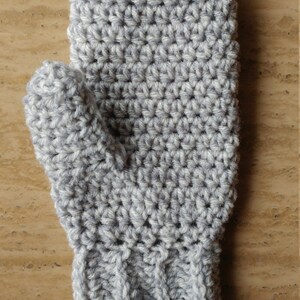May include: A gray crocheted mitten with a ribbed cuff. The mitten is made with a textured stitch.