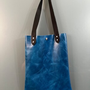 May include: A blue leather tote bag with black leather straps and silver hardware.