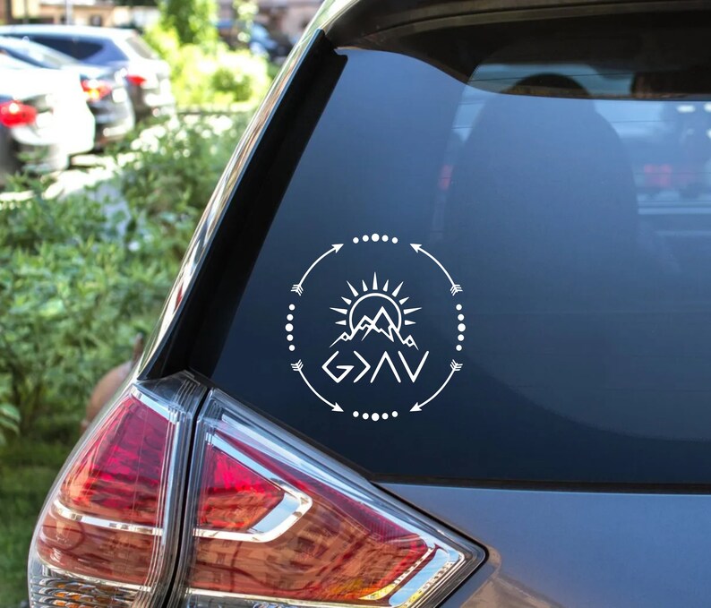 May include: White vinyl decal with a mountain range, sun, and arrows forming a circle around the text "God is greater than the highs and lows".