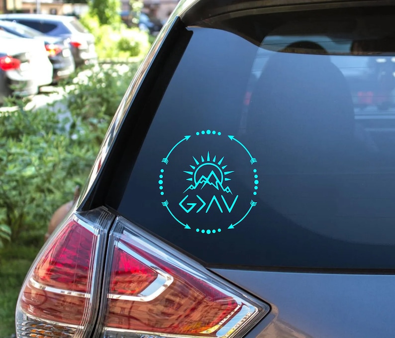 May include: A teal blue vinyl decal with a mountain range, sun, and arrows surrounding the text "God is Greater Than the Highs and Lows".